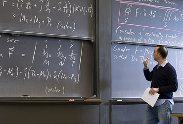 A professor at a series of blackboards working out a mathmatical calculation