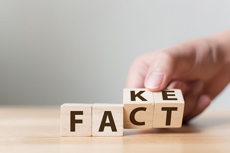 A set of four alphabet blocks on a table with the first two showing the letters F and A; and the last two being turned from one side to another, going from KE to CT (making the word change from fake to fact)