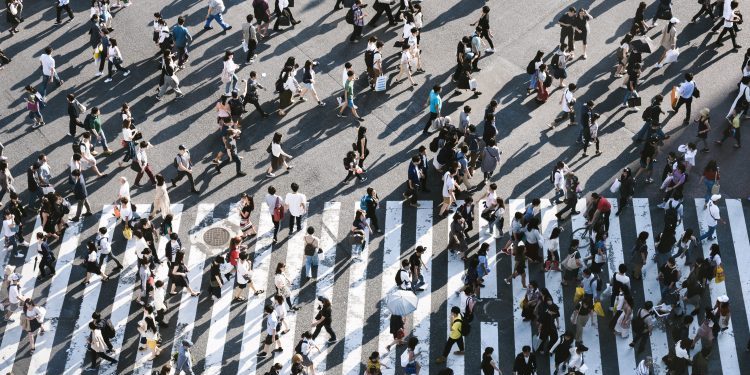 a large group of people seen from overhead crossing a street in multiple directions
