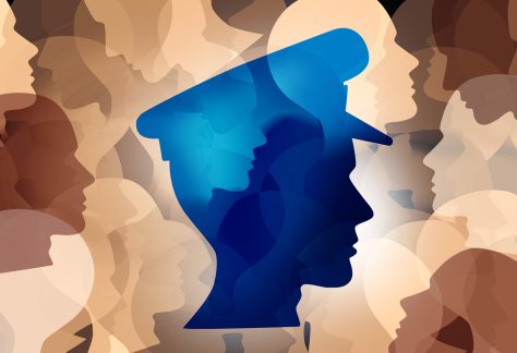 An illustration with the outline of a person's head in profile wearing a police hat, all in blue, over a background of several people's head outlines layered over each other facing every direction, in the many different skin tone colors.