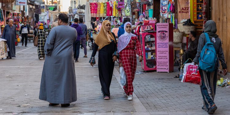 Egyptian women walk through a market